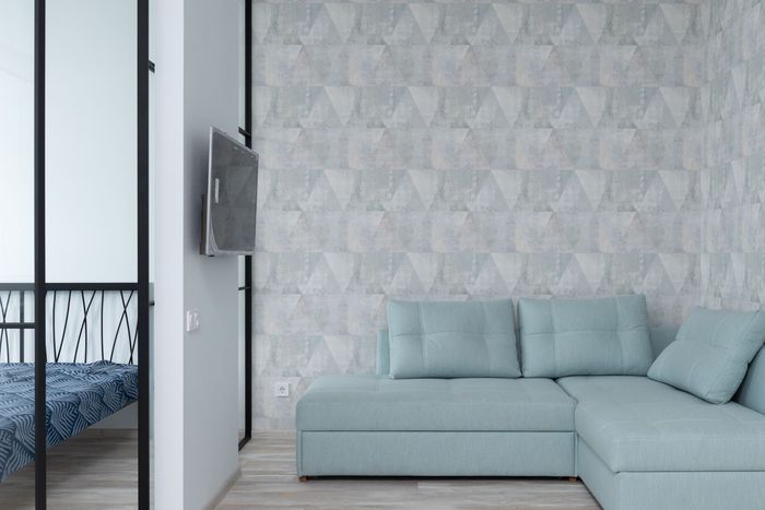 Modern living room with grey geometric wallpaper behind a pale-blue sofa