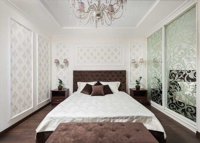Classic bedroom with grey damask wallpaper panels flanking a tufted headboard