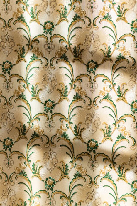 Close-up of embossed cream floral wallpaper texture in raking light