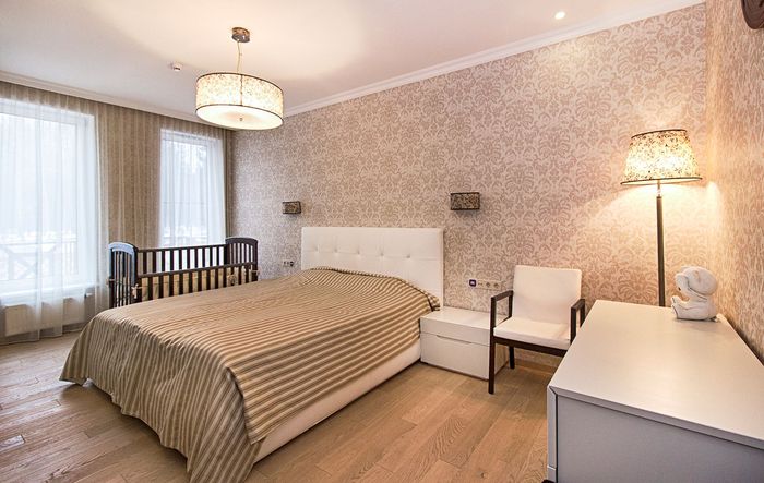 Bedroom with warm beige damask wallpaper and a white upholstered headboard