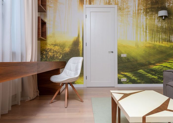 Study nook with a sunlit forest mural wallpaper behind a white desk and chair
