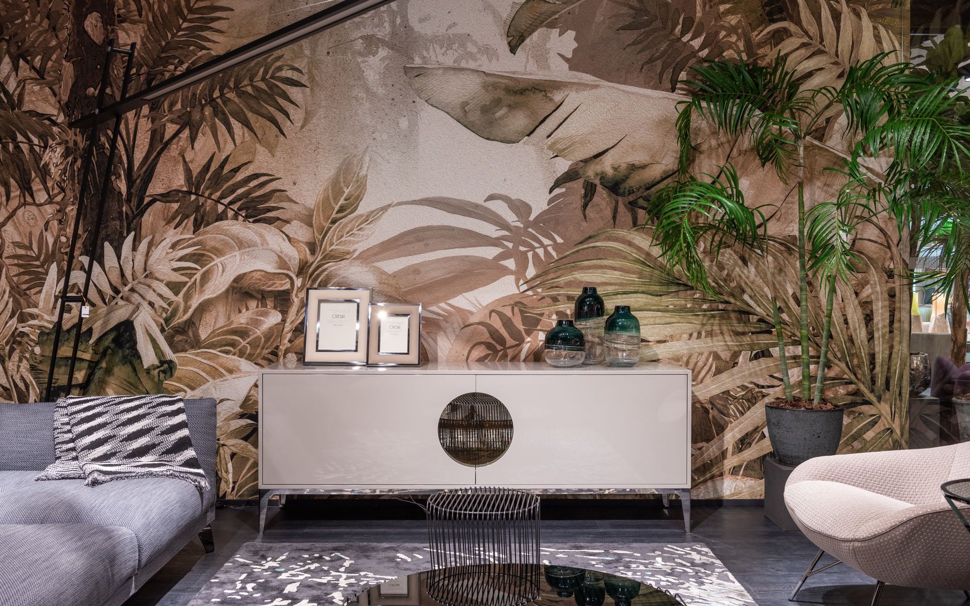 White sideboard set against a sepia-toned tropical botanical mural wallpaper in a modern residential living room