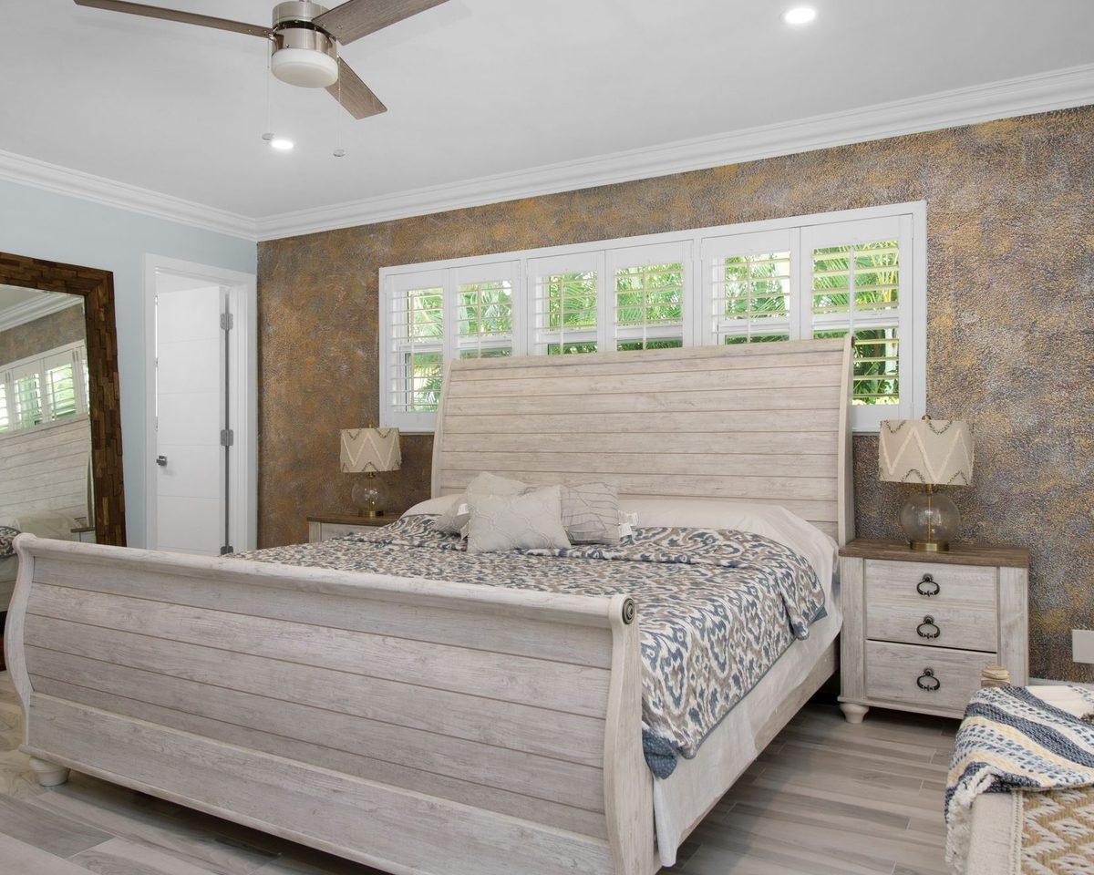 Bedroom with soft taupe damask wallpaper, a whitewashed bed and a floor mirror