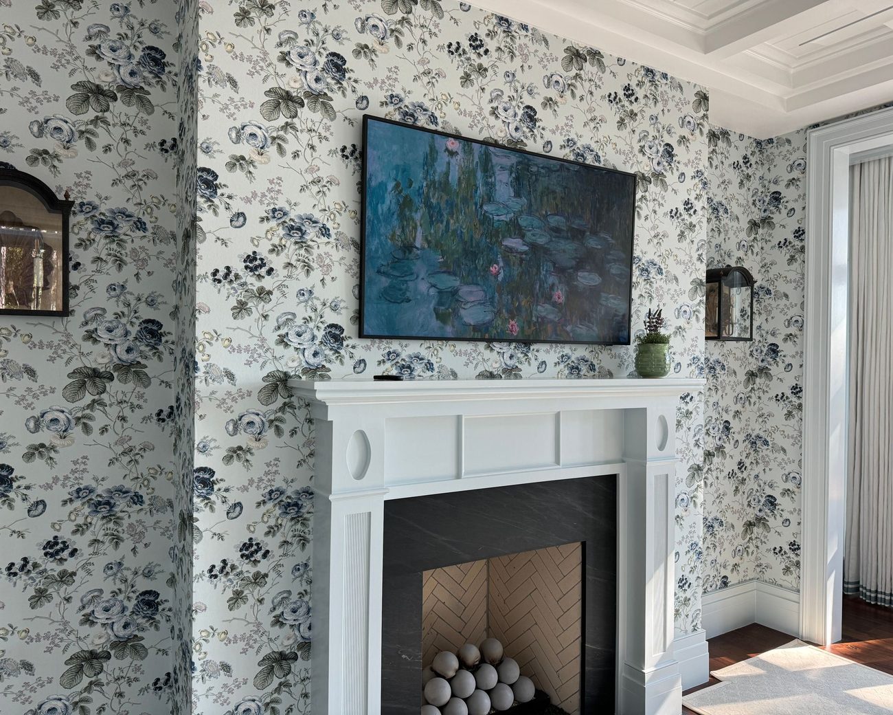 Living room with blue-and-green floral wallpaper beside a white fireplace